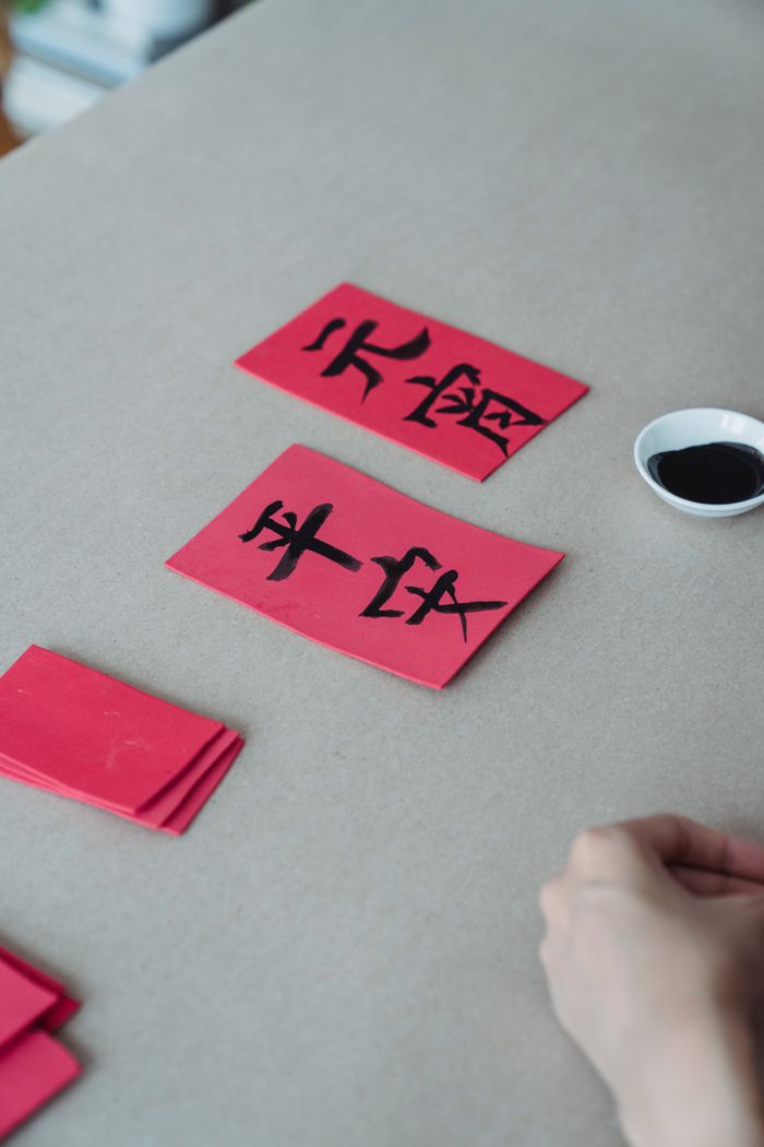 Close-up of red cards with Chinese calligraphy on a table, showcasing traditional craft.